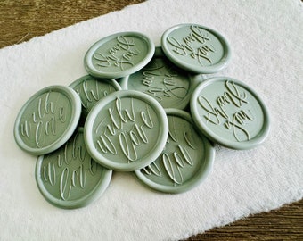 May include: A pile of sage green wax seals with the words "Thank You" and "With Love" written in white calligraphy.