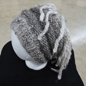 May include: A gray and white knitted hat with long white yarn strands hanging down.
