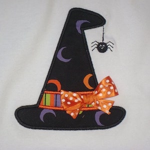 May include: A black witch hat with a purple, orange, and green striped band, a white polka dot orange bow, and a black spider hanging from the top.