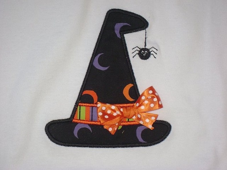May include: A black witch hat with a purple, orange, and green striped band, a white polka dot orange bow, and a black spider hanging from the top.