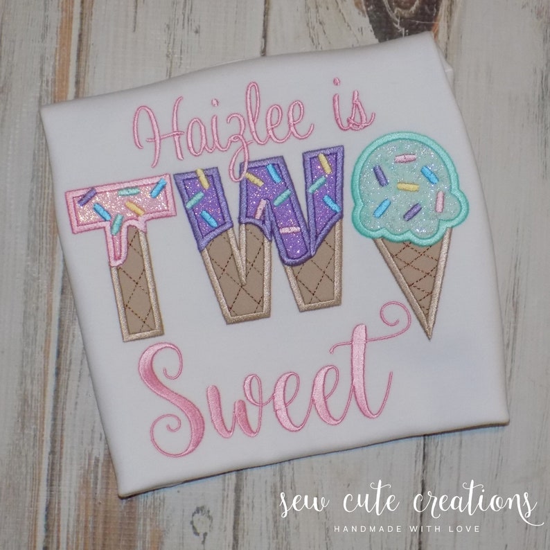 May include: A white t-shirt with pink embroidery that says "Haizlee is TWO Sweet" with ice cream cone shaped letters and a single ice cream cone on the right side.
