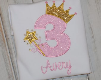 May include: White t-shirt with a pink glitter number 3, a gold glitter crown, and a gold star wand. The name "Avery" is embroidered in pink script. The text "sew cute creations" and "handmade with love" are at the bottom.