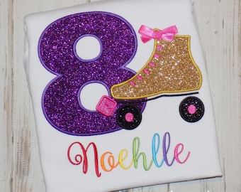 May include: Purple glitter number eight with a gold glitter roller skate and pink bow. The name "Noelle" is embroidered in rainbow colors below the number and skate.