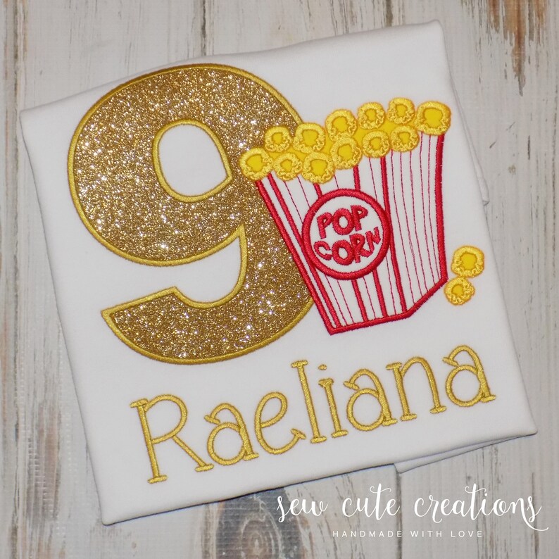 May include: Gold glitter number nine with a red and white striped popcorn bucket and the name Raelian in gold glitter. The text "Sew Cute Creations Handmade with Love" is at the bottom of the image.