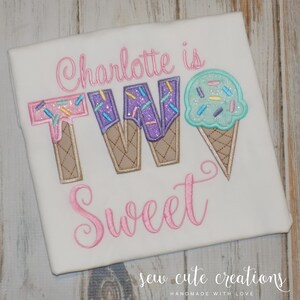 May include: A white t-shirt with pink embroidery that says "Charlotte is Two Sweet" with ice cream cone shaped letters and a single ice cream cone graphic. The ice cream cones have sprinkles and a brown waffle cone.