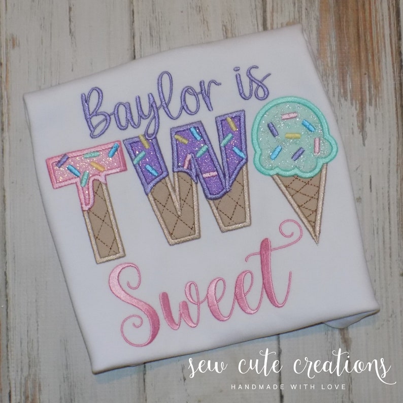 May include: White t-shirt with the text "Baylor is TWO Sweet" in pink, purple, and blue embroidery. The number two is made to look like ice cream cones with sprinkles.