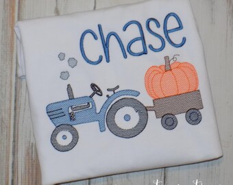 May include: A white t-shirt with blue embroidery of a tractor pulling a wagon with a pumpkin. The text "chase" is embroidered in blue above the tractor.