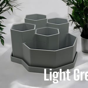 May include: Light grey hexagonal planter with six individual pots, ideal for small plants or succulents. The planter has a tray to catch excess water.