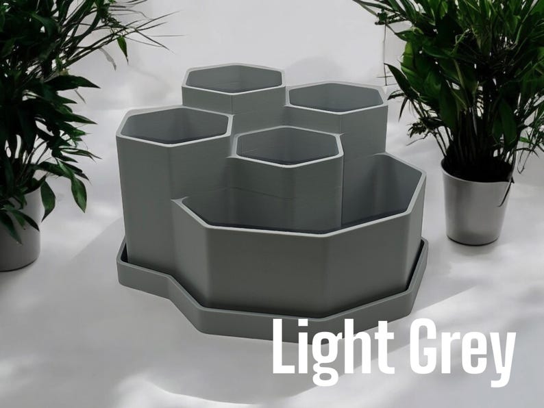May include: Light grey hexagonal planter with six individual pots, ideal for small plants or succulents. The planter has a tray to catch excess water.