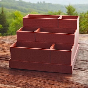 May include: A tiered, rectangular, brown planter with six individual compartments. The planter is made of a textured material and is sitting on a wooden surface.