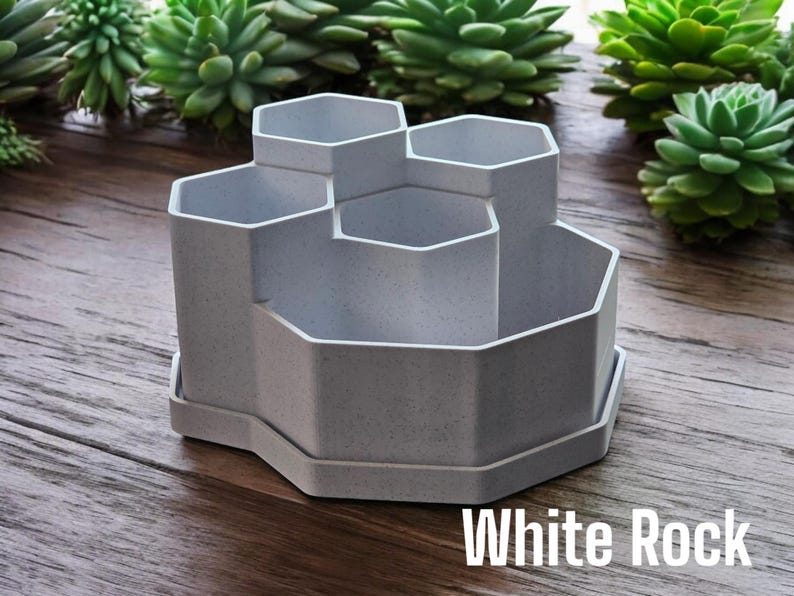 May include: A white hexagonal desk organiser with six compartments. The organiser is made of a textured material and has a base.