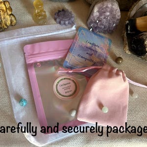 May include: A pink resealable pouch with a clear window and a round label reading CatDipanna, accompanied by a small pink drawstring bag and a rectangular card featuring the text I radiate calmness and tranquility, all presented together.