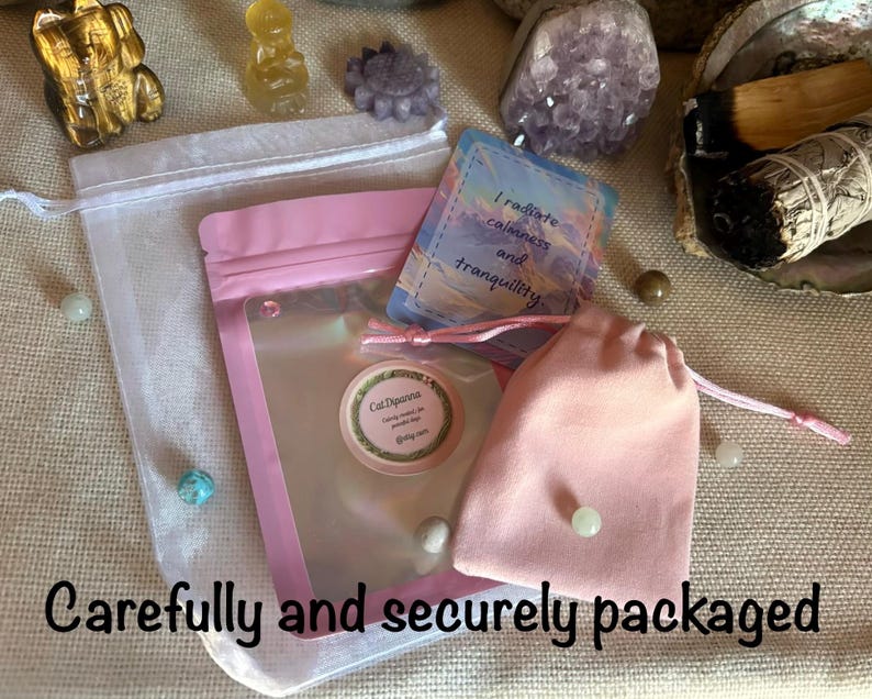 May include: A pink resealable pouch with a clear window and a round label reading CatDipanna, accompanied by a small pink drawstring bag and a rectangular card featuring the text I radiate calmness and tranquility, all presented together.