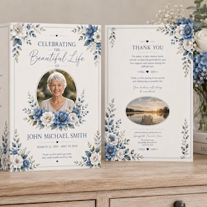 May include: A memorial card with a photo of a woman, surrounded by blue and white floral accents. The text reads "Celebrating the Beautiful Life of John Michael Smith, March 12, 1950 - May 10, 2024." The card is open, revealing a thank you message.