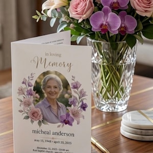 May include: A white funeral program card featuring the text in loving Memory, a portrait of an older person, and the name micheal anderson with dates may 15, 1948 - april 20, 2025, surrounded by a floral wreath of pink roses and purple orchids.