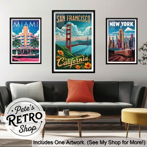 K&ouml;nnte beinhalten: Drei gerahmte Kunstdrucke mit Stadtansichten. Die Drucke zeigen Miami mit einem Retro-Hotel, San Francisco mit der Golden Gate Bridge und New York mit einem Zug. Die Kunstwerke sind &uuml;ber einem schwarzen Sofa mit bunten Kissen ausgestellt.