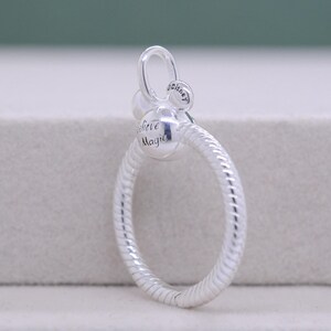 Pu&ograve; includere: Un charm argentato dal design circolare. Il charm presenta le parole "Believe Magic" e una piccola testa di Topolino. L'anello &egrave; strutturato con un motivo a spirale. Il charm ha un anello nella parte superiore per l'attacco.