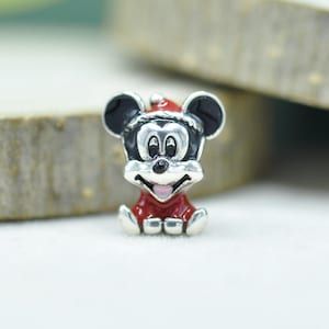 May include: A silver-toned metal charm shaped like a cartoon mouse head wearing a red Santa hat. The design features black enamel on the ears and eyes, a red enamel body, and a small pink accent on the open mouth, creating a festive holiday character.