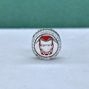 Può includere: Un charm in argento con un design a casco di Iron Man rosso e bianco. Il charm rotondo ha un bordo di pietre trasparenti.