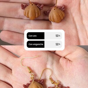 Pode incluir: Brincos feitos &agrave; m&atilde;o com um design texturizado castanho claro e detalhes em vermelho escuro. Os brincos est&atilde;o dispon&iacute;veis com argolas ou ganchos dourados. A imagem inclui um gr&aacute;fico com o texto "Con aro" e "Con enganche".