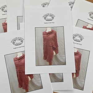 May include: A stack of printed knitting patterns for a Staghorn Cable Wrap. The pattern is from Willow Knits.