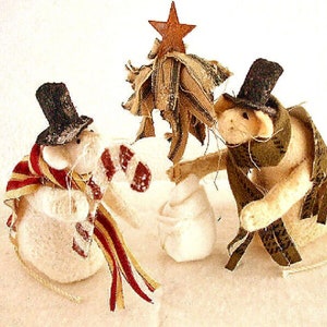 May include: Two white felt mice wearing black top hats and scarves, one holding a candy cane, standing in front of a small felt Christmas tree with a red star on top.