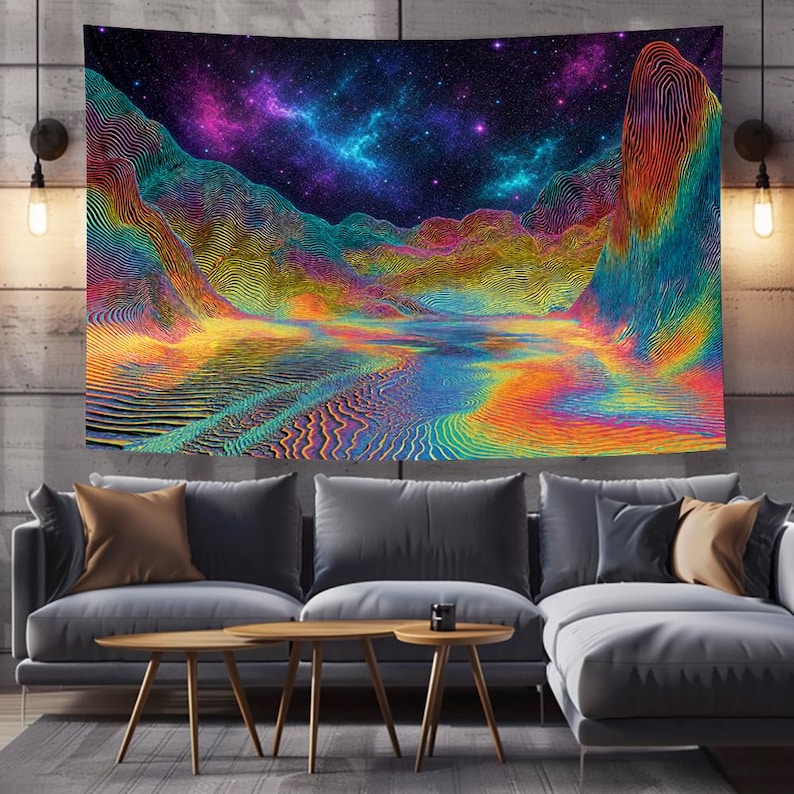 May include: A vibrant tapestry depicting a colorful landscape with mountains and a starry night sky. The artwork features a spectrum of colors, including blues, purples, yellows, and oranges, creating a psychedelic effect. The tapestry is displayed on a wall above a gray sofa.