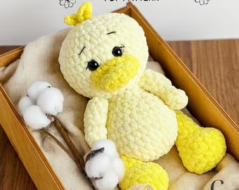 Könnte beinhalten: Ein handgefertigtes, hellgelbes Häkelenten-Spielzeug mit gelbem Schnabel, Füßen und Kopfteilen. Die Ente befindet sich in einer Holzkiste mit Baumwollstielen. Der Text "MY CUTE CROCHET PDF PATTERN" steht über der Ente.