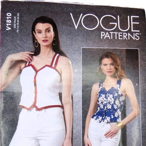 May include: Vogue Patterns sewing pattern featuring two top designs. One top is white with red trim and straps, the other is blue with a floral print. The pattern includes sizes F5 (16-18-20-22-24).