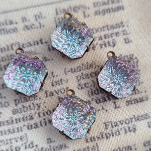 May include: Four iridescent glass charms with a floral pattern, each with a bronze loop for hanging. The charms are a mix of blue, purple, and green.
