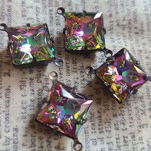 May include: Four iridescent square-shaped glass rhinestones with metal settings and loops. The rhinestones have a rainbow effect.