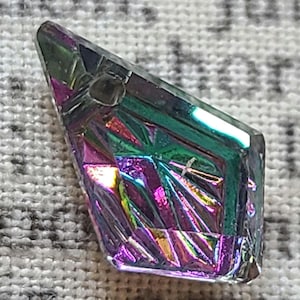 Puede incluir: Colgante de cristal iridiscente con un diseño geométrico facetado. El colgante es una mezcla de colores morado, verde y dorado. Tiene un pequeño agujero en la parte superior para ensartar. El cristal mide aproximadamente 3.8 cm de largo.