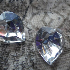 May include: Two clear crystal heart-shaped charms. The charms are faceted and have a shiny finish.