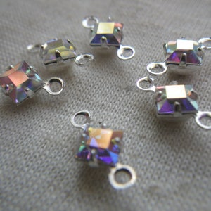 May include: Six iridescent square-shaped crystal connectors with silver metal loops. The connectors are perfect for jewelry making or adding a touch of sparkle to crafts.