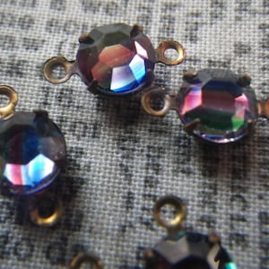 May include: Four iridescent glass beads with gold metal loops. The beads are a dark blue color with a rainbow sheen.