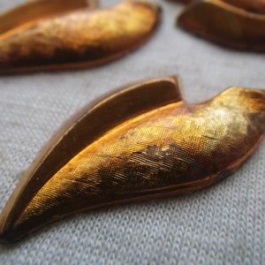 May include: Four gold-colored metal leaf-shaped embellishments with a textured surface.