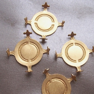 May include: Four gold-toned metal embellishments with a circular design and four points. Each embellishment has a raised, textured border around the centre circle.