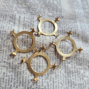 May include: Four gold-toned metal rings with a decorative design. Each ring has five points and a circular center.