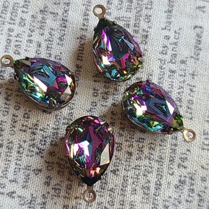May include: Four iridescent teardrop-shaped crystal pendants with antique bronze-colored metal loops. The crystals have a rainbow effect with shades of purple, blue, green, and red.