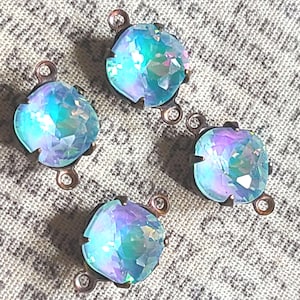 May include: Four iridescent blue glass rhinestones with copper-toned metal settings. Each rhinestone has three loops for attaching to jewelry or other crafts.