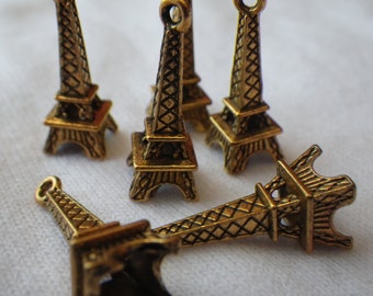 May include: Six gold-colored Eiffel Tower charms, each with a detailed design. The charms are small and perfect for adding a touch of Parisian style to jewelry or crafts.