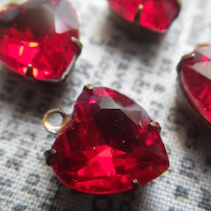 Peut inclure: Quatre embellissements en verre en forme de cœur rouge avec des montures métalliques. Les embellissements ont un design facetté et sont parfaits pour ajouter une touche d'éclat aux travaux manuels et aux bijoux.