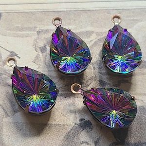 May include: Four iridescent teardrop-shaped pendants with a rainbow effect. Each pendant has a bronze-colored metal frame and a small loop at the top for hanging. The pendants are faceted, catching and reflecting light.