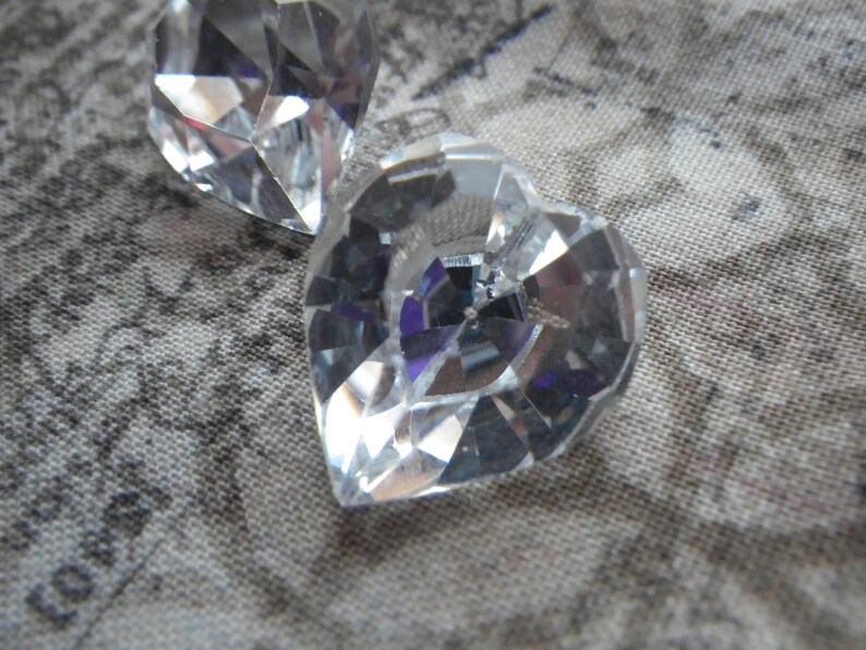 May include: Two clear crystal heart-shaped ornaments with a faceted design.
