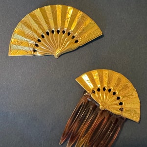 May include: Two gold fan-shaped hair combs. One comb is a simple fan shape, the other has a comb attached to the bottom.