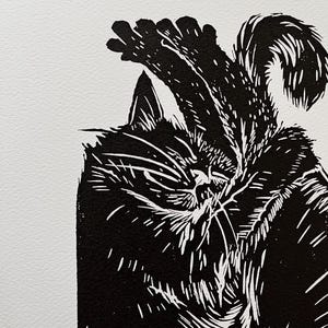 May include: Black and white linocut print of a cat sleeping with its paw over its head.