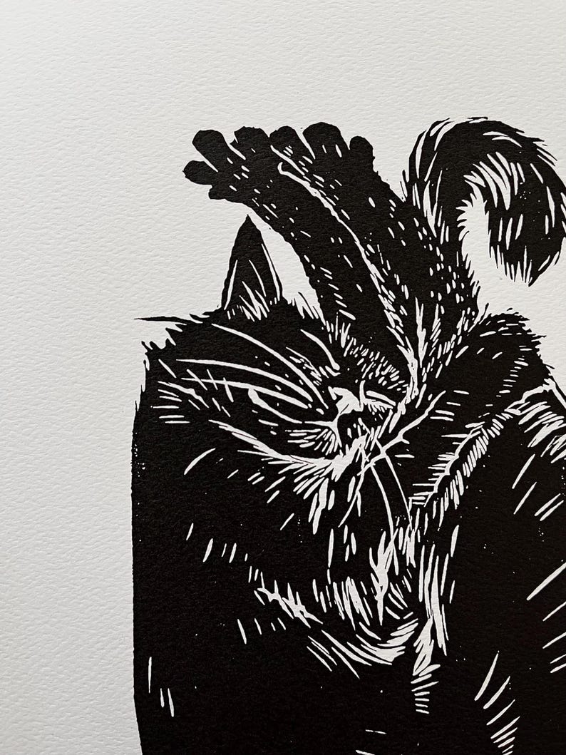 May include: Black and white linocut print of a cat sleeping with its paw over its head.