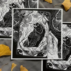 May include: Black and white art print featuring a crow illustration within a tarot card design. The card reads "The Fool" and includes botanical elements. The artwork has a detailed linework style and is set against a neutral background.