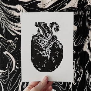 May include: Black and white linocut print of a cat curled up sleeping. The cat is depicted in a simple, minimalist style.