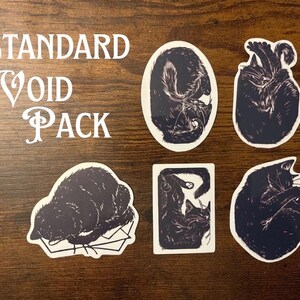 Puede incluir: Un conjunto de cinco pegatinas de gatos negros con varias posturas de sue&ntilde;o y descanso, acompa&ntilde;adas del texto blanco "STANDARD VOID PACK" impreso en una fuente serif decorativa. Las pegatinas est&aacute;n troqueladas con bordes blancos.